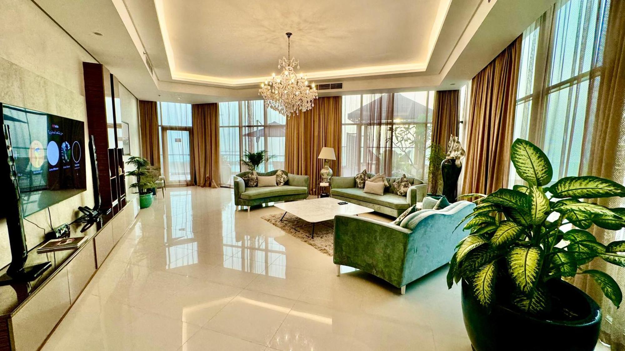Lagoona Beach Luxury Resort And Spa Манама Екстериор снимка The photo depicts a spacious and elegantly designed living room. The room features large windows allowing natural light to flood in, accompanied by sumptuous curtains. The furniture includes a pair of soft green sofas and a centerpiece coffee table s