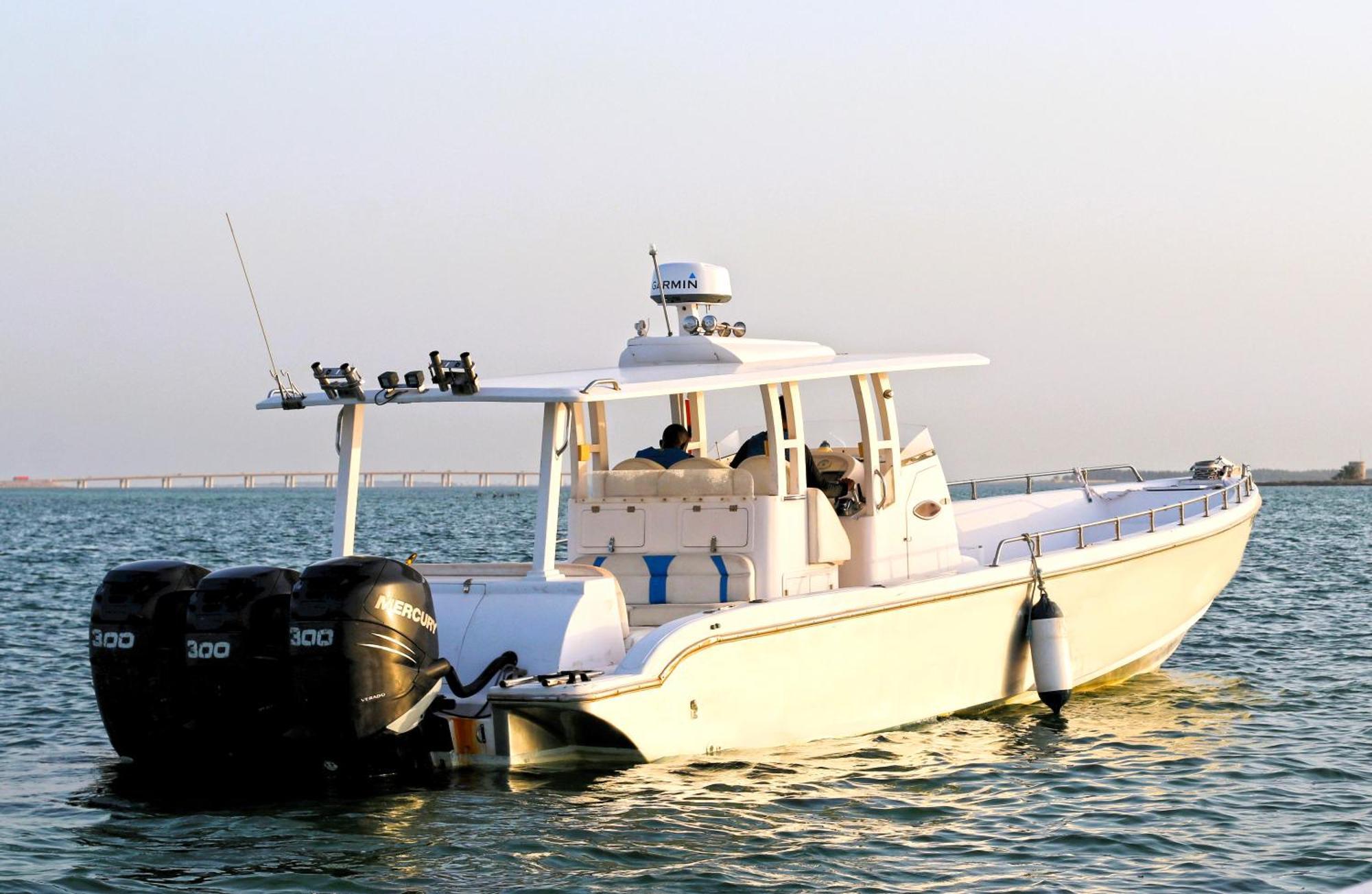 Lagoona Beach Luxury Resort And Spa Манама Екстериор снимка The photo shows a large, white motorboat equipped with three powerful outboard engines at the stern. The boat has a sleek design, with a spacious open deck and a covered cabin area that likely provides shelter and controls for navigation. The scene i