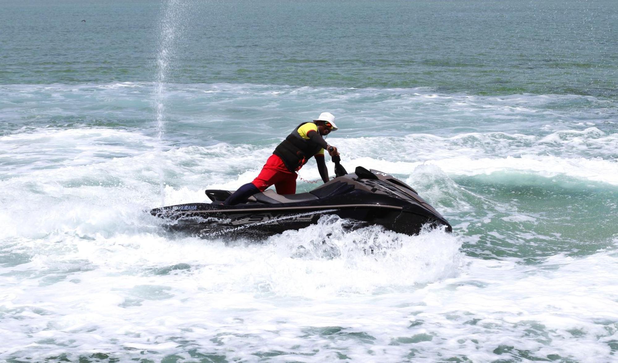 Lagoona Beach Luxury Resort And Spa Манама Екстериор снимка The photo shows a person riding a jet ski on the water. The rider is positioned upright, leaning forward with one hand on the handlebars, while the jet ski creates splashes of white foam around it. The water appears choppy, likely due to the motion o