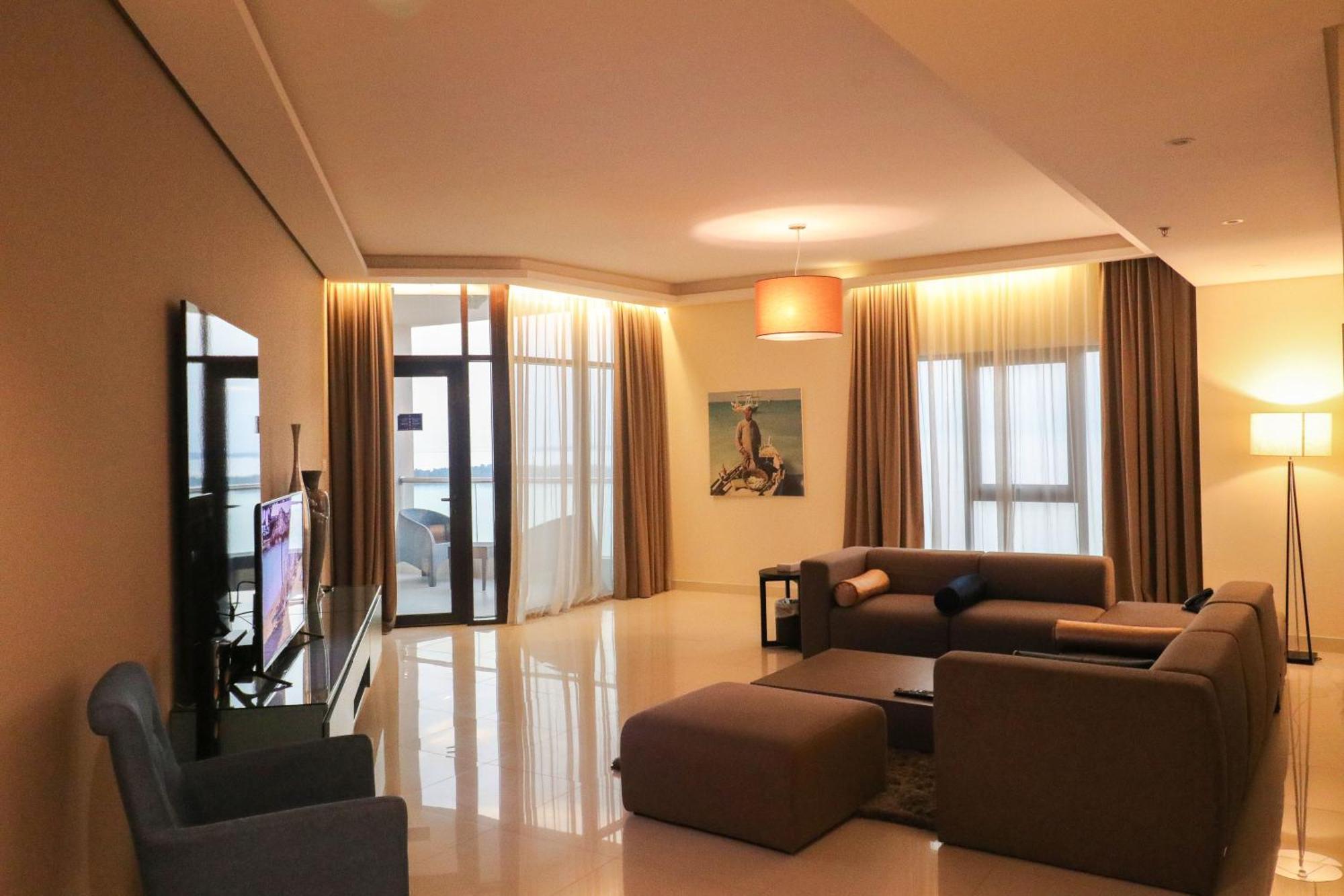 Lagoona Beach Luxury Resort And Spa Манама Екстериор снимка The photo shows a modern living room with a spacious and elegant design. It features a large couch in neutral tones, a soft ottoman, and a stylish coffee table. The walls are painted in a light color, and there are large windows with sheer curtains a
