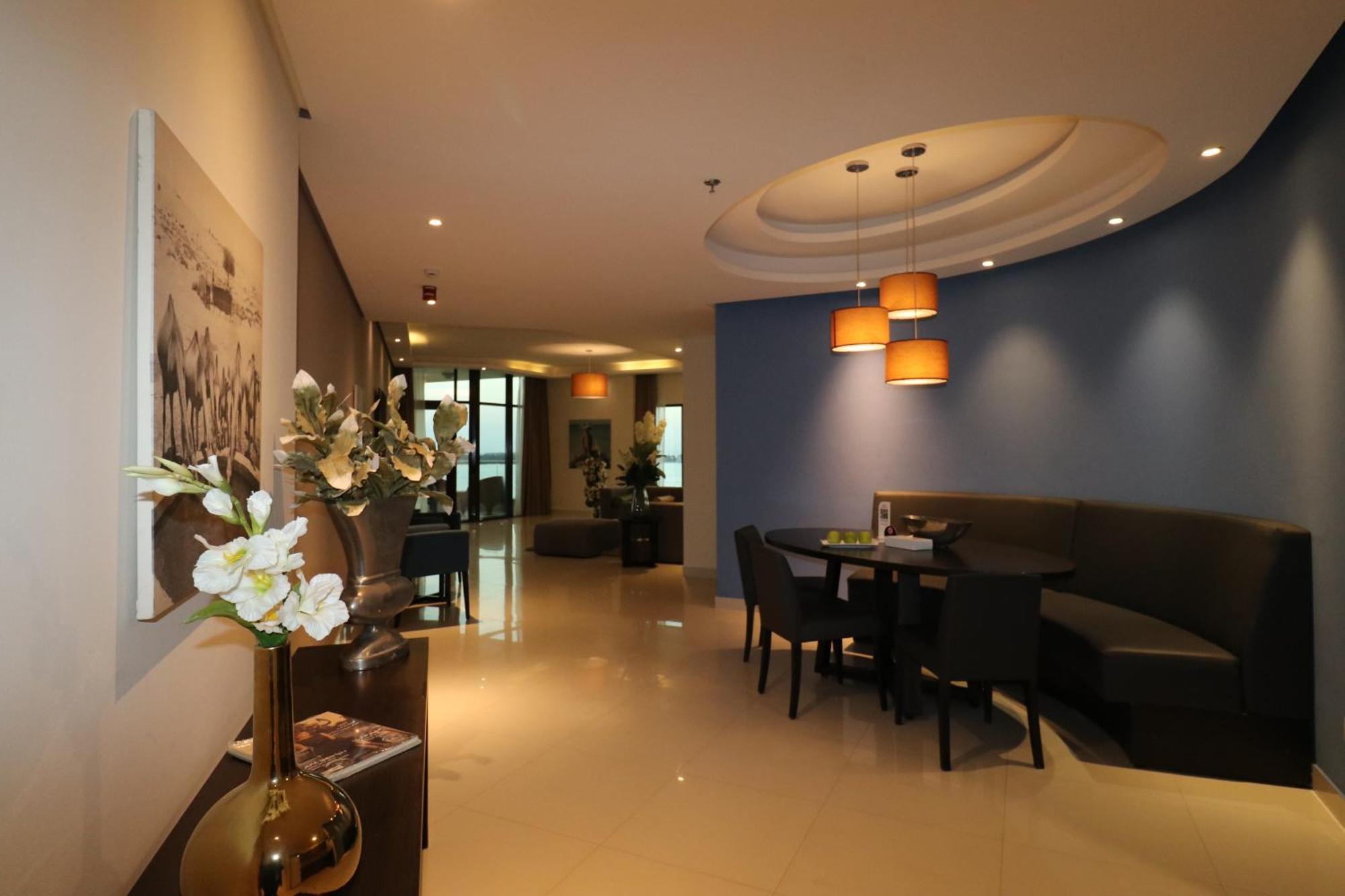 Lagoona Beach Luxury Resort And Spa Манама Екстериор снимка The photo showcases an interior space, likely a modern lounge or reception area. It features a combination of soft lighting, neutral-colored walls, and decorative elements. There are elegant light fixtures hanging from the ceiling, and a curved blue 